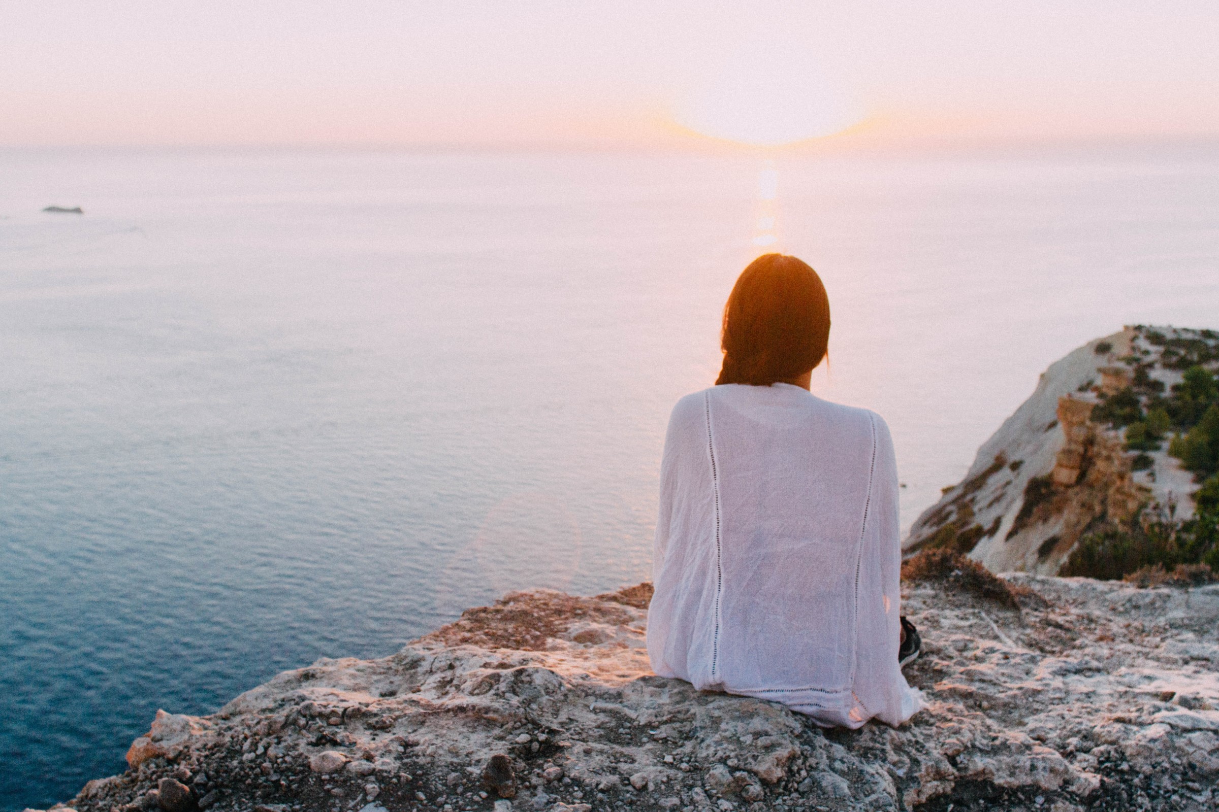 girl-sitting-on-cliffside-by-ocean