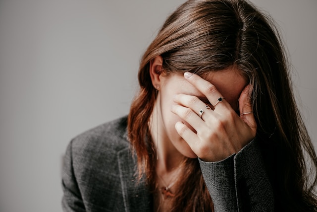 A woman with her hand covering her face in stress.